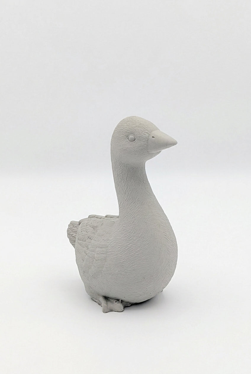 A small matte gray goose figurine or candle holder, shown from the side against a seamless light gray studio background.